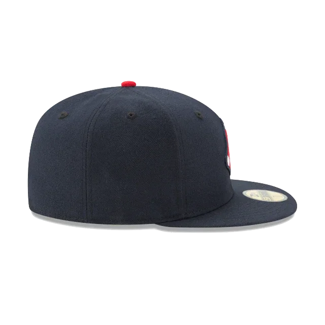 Navy blue fitted hat with flat brim and red top button, side profile view