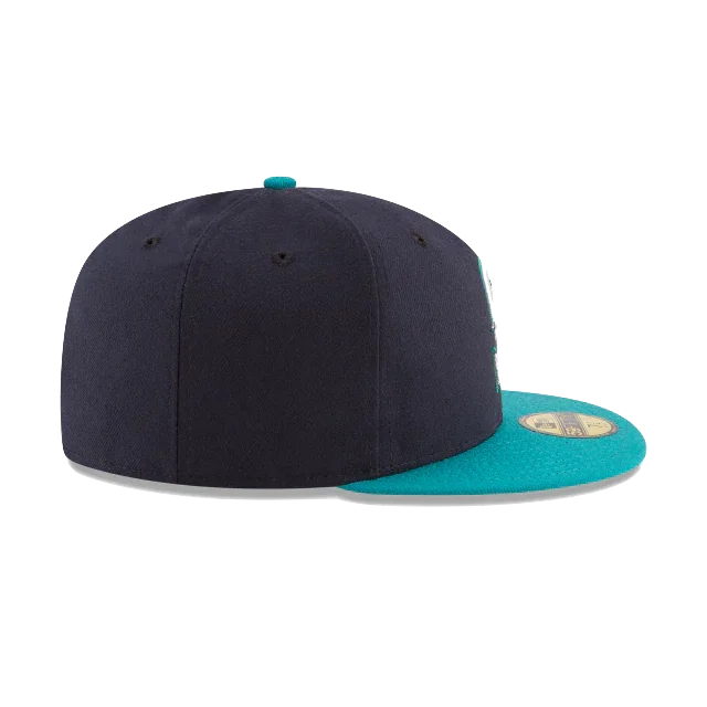 Black and teal fitted flat brim sports cap, side view, with gold sticker on the visor