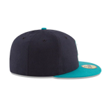 Black and teal fitted flat brim sports cap, side view, with gold sticker on the visor