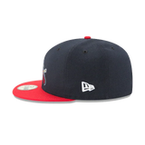 Navy blue snapback cap with red flat brim, side logo embroidery, and sticker on visor