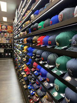 Rows of new era baseball caps in assorted colors and team logos line the shelves.