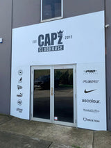 White exterior wall panel with black text and logos for capz clubhouse, featuring brand emblems including puma, nike, flexfit, and brixton.