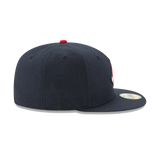 Navy blue fitted hat with flat brim and red top button, side profile view